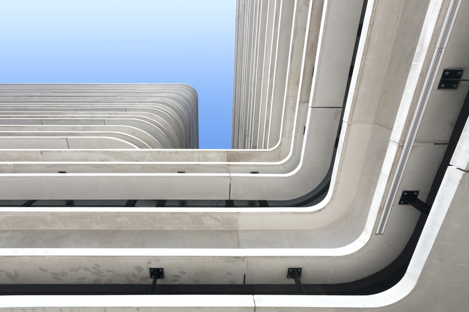 Perspective en contre-plongée d'un bâtiment moderne aux lignes courbes et épurées.