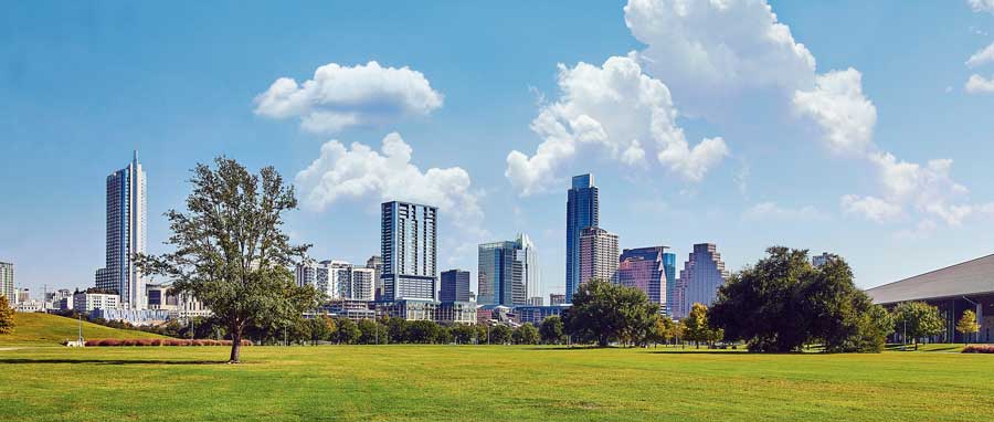 Vue panoramique d'une skyline urbaine avec un grand parc verdoyant au premier plan.