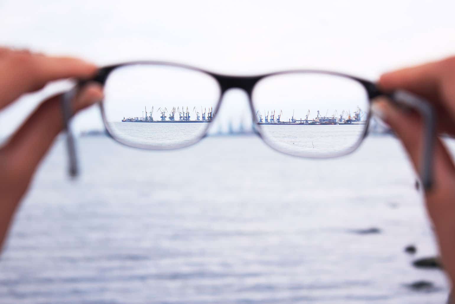 Des lunettes mettent au point des grues du port sur un arrière-plan flou en bord de mer