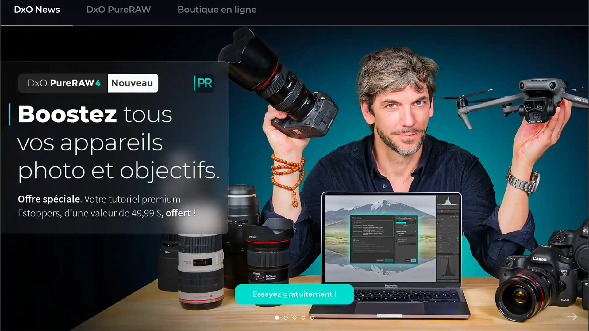 Homme tenant un appareil photo et un drone, avec un ordinateur portable affichant un logiciel de retouche photo, entouré d'objectifs.