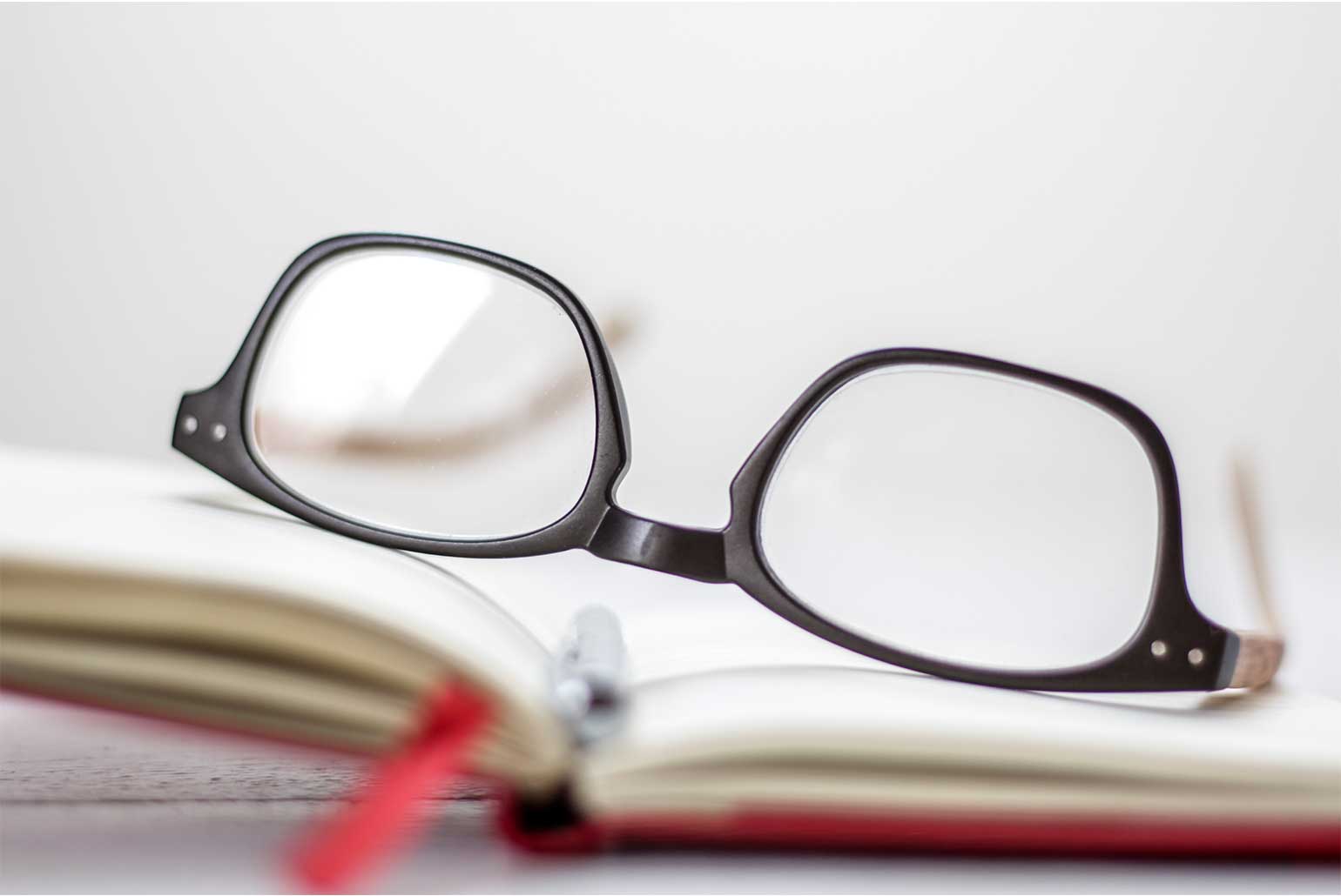 Lunettes posées sur un carnet ouvert avec un marque-page rouge