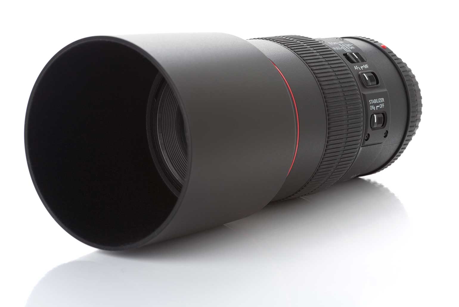 Objectif d'appareil photo professionnel avec pare-soleil et boutons de réglage sur un fond blanc.