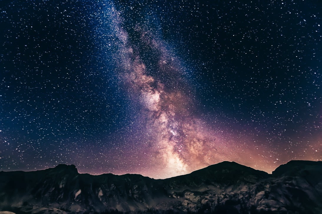 Voie lactée étincelante au-dessus d'une silhouette de montagnes la nuit