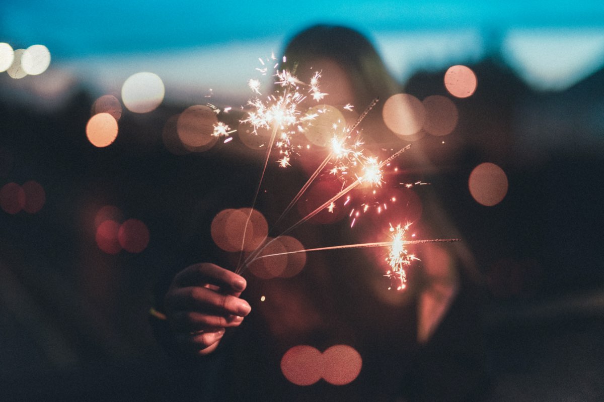 Personne tenant des cierges magiques allumés avec un effet bokeh en arrière-plan
