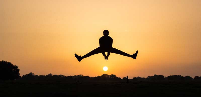 Silhouette de personne en plein saut capturée au sommet du geste, ciel de coucher de soleil en arrière-plan