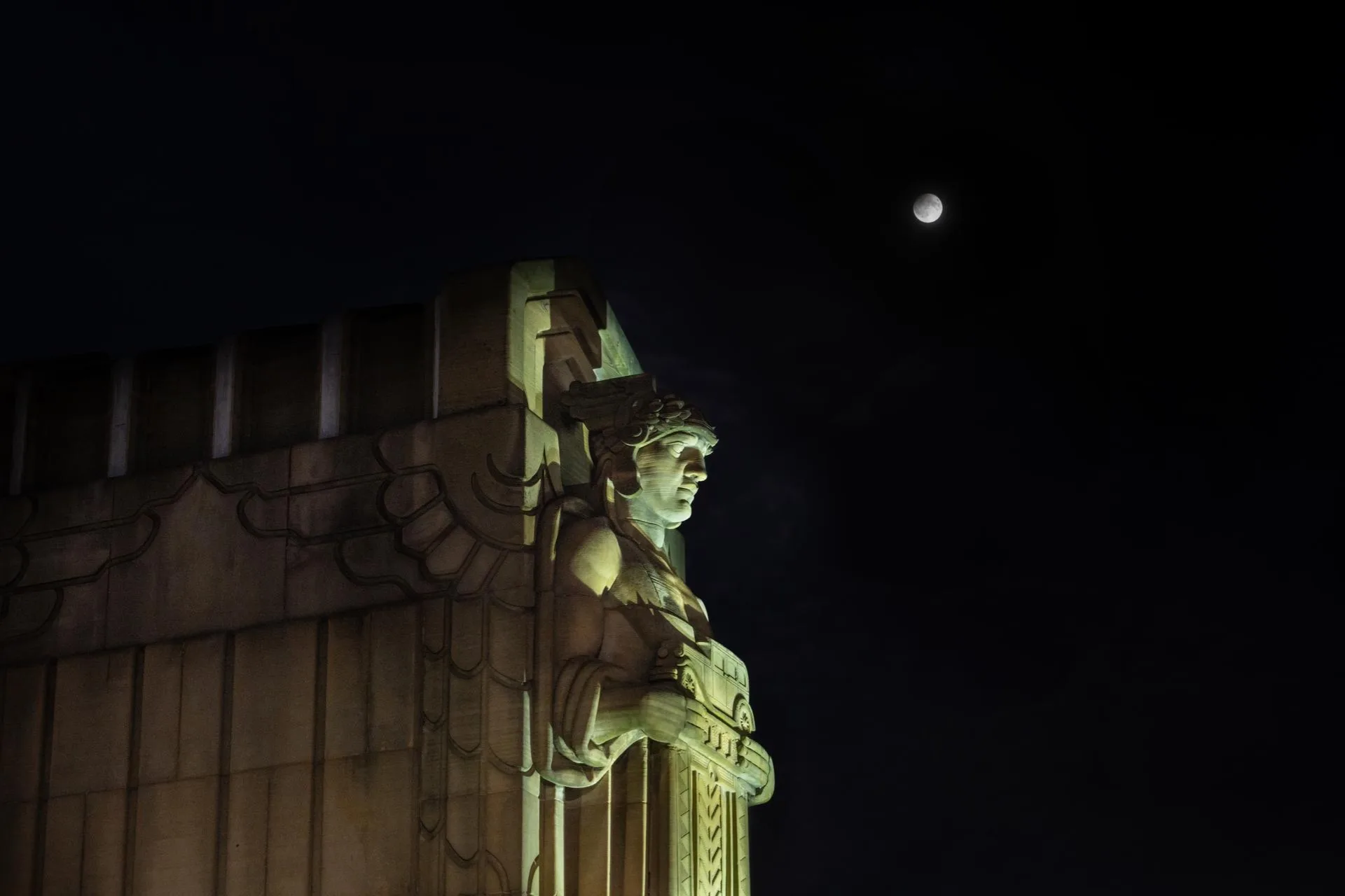 Éclipse partielle de Lune au-dessus d'une statue monumentale éclairée
