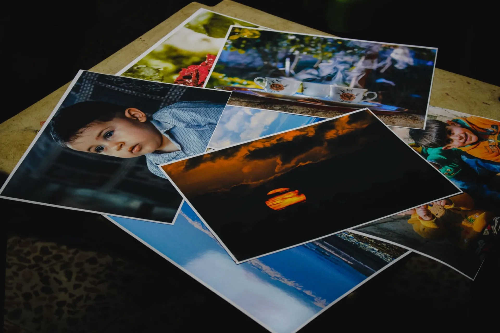 Tirages photo étalés sur une table : portrait, paysage et coucher de soleil