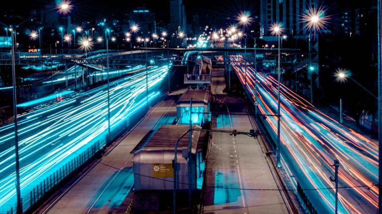 Longue exposition de lumière de phares de voitures sur une autoroute urbaine la nuit.