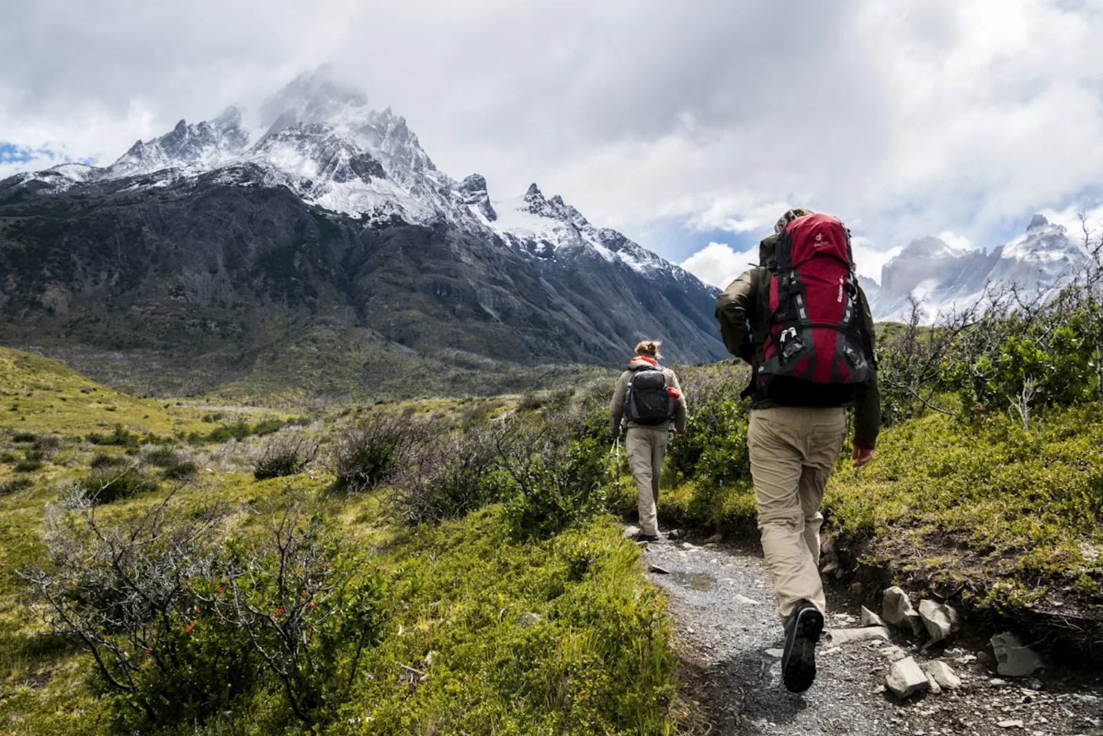 Deux randonneurs avec sacs à dos rouges devant un massif montagneux brumeux en Patagonie