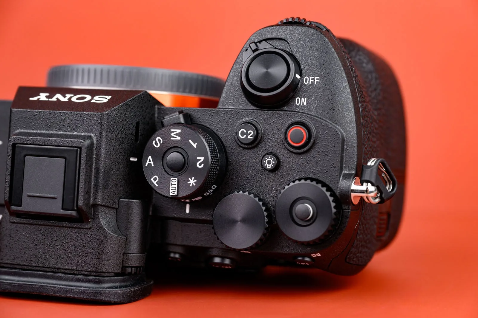 Sony Alpha 7R VI vu de dessus sur fond corail, molette PSAM, boutons rétro-éclairés