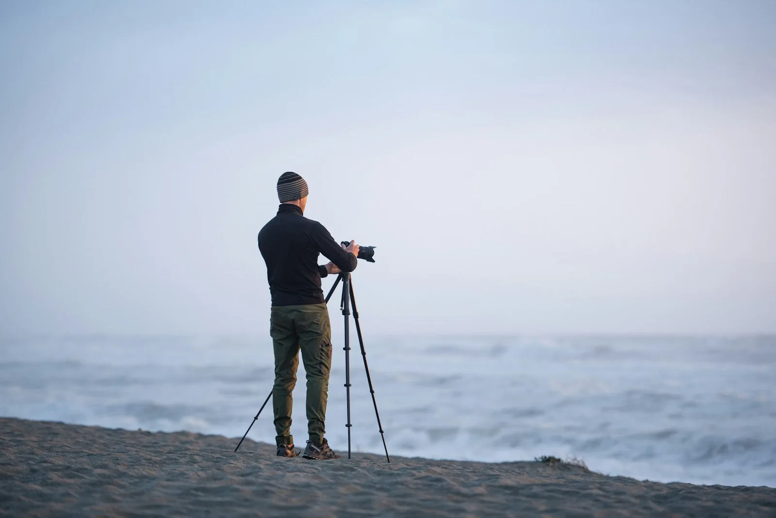 Photographe en bord de mer avec trépied Peak Design déployé, lumière du matin