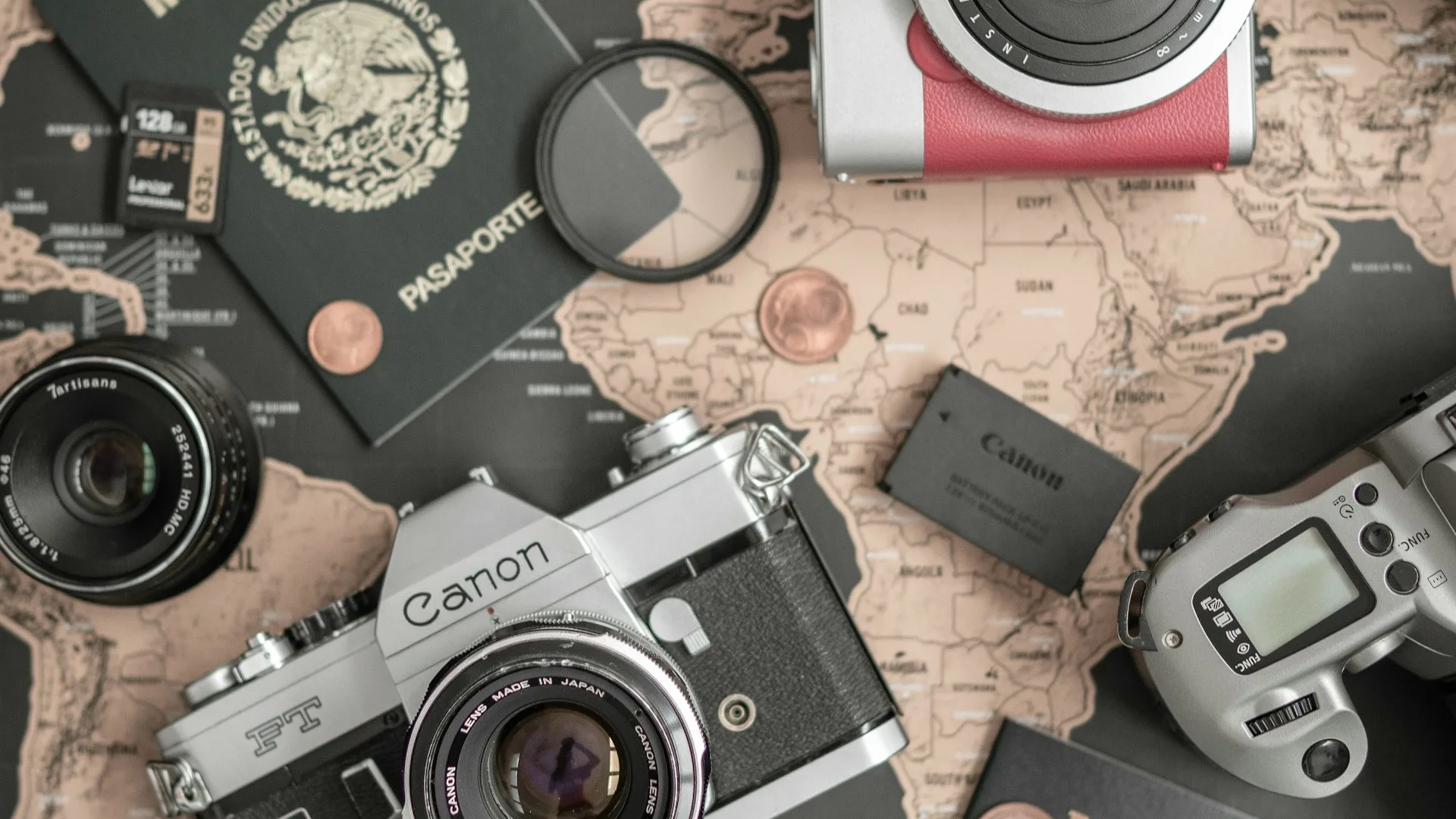 Appareils photo, objectifs et accessoires posés à plat sur une carte du monde