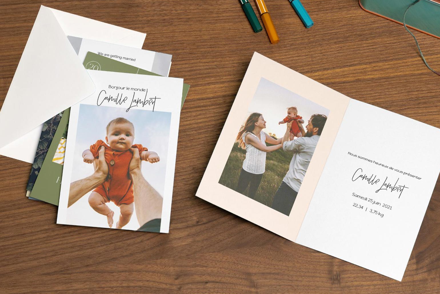 Cartes de naissance et faire-part posés sur une table en bois avec des photos de famille.