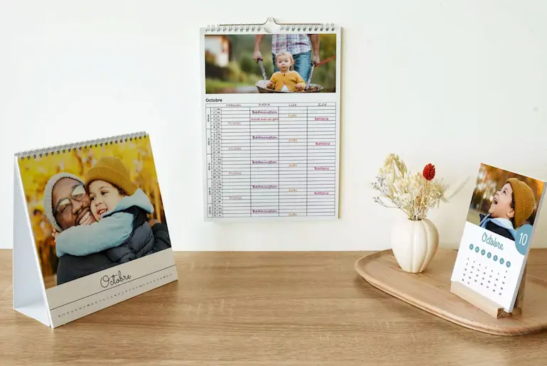Trois calendriers de bureau et mural présentant des photos d'octobre sur une table en bois.
