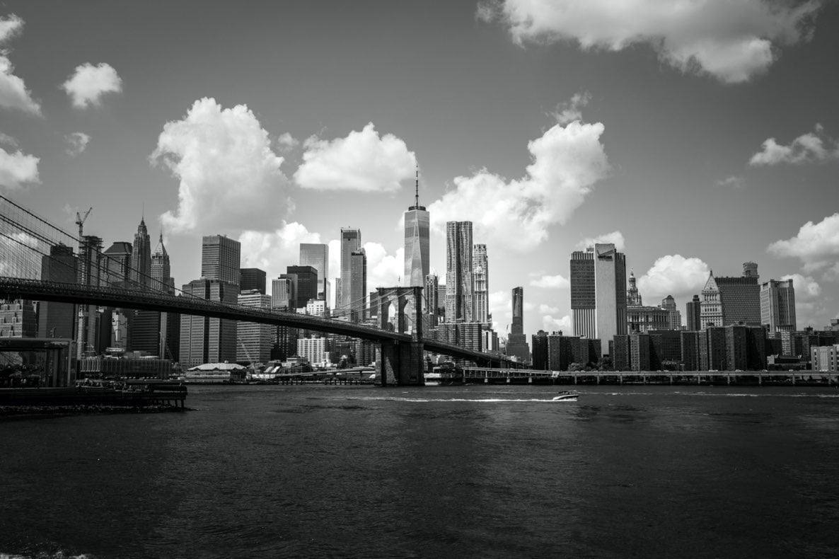 Vue en noir et blanc du pont de Brooklyn et de la skyline de Manhattan avec un ciel nuageux.