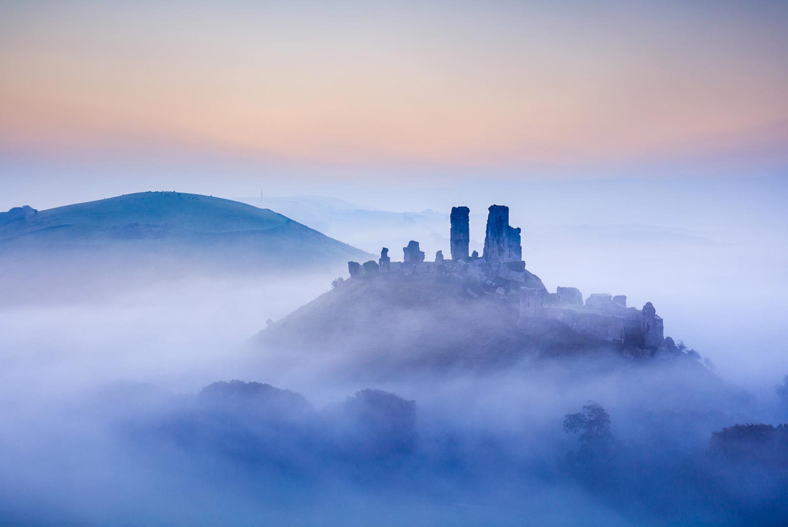 Ruines de château émergeant de la brume au lever du soleil.