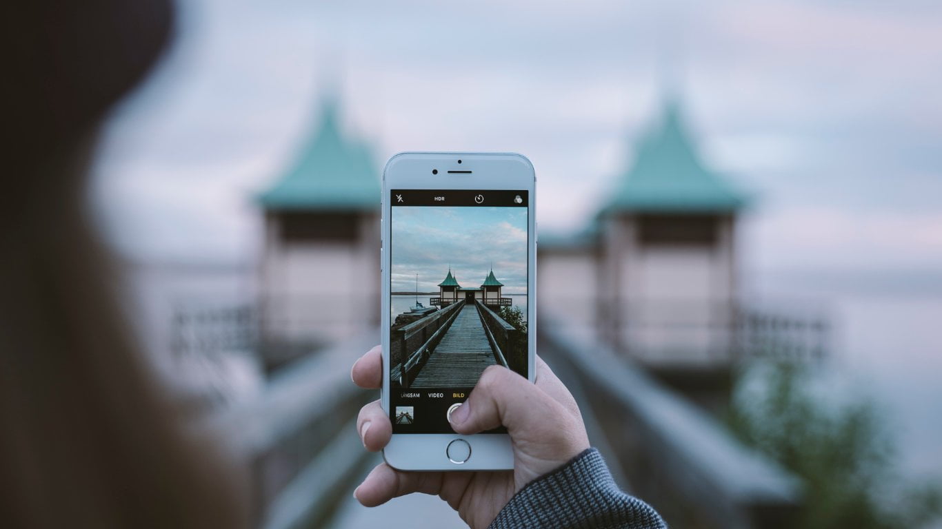 Personne prenant une photo de bâtiments avec un smartphone sur une passerelle floue en arrière-plan