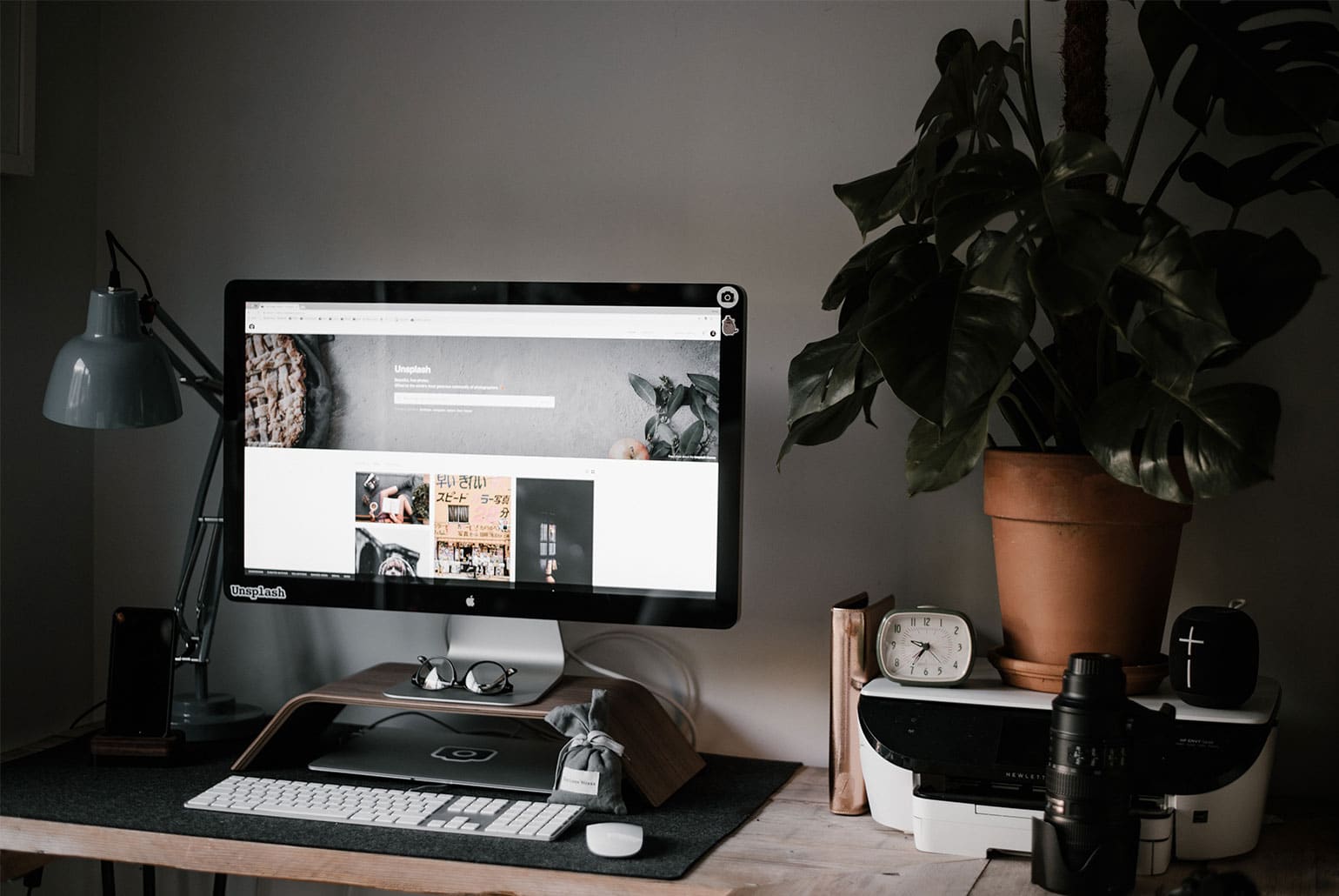 Bureau moderne avec ordinateur, plante en pot et accessoires technologiques.