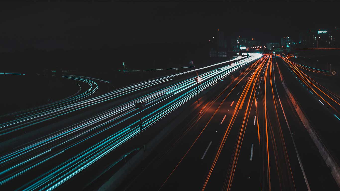 Traînées lumineuses de voitures sur une autoroute la nuit
